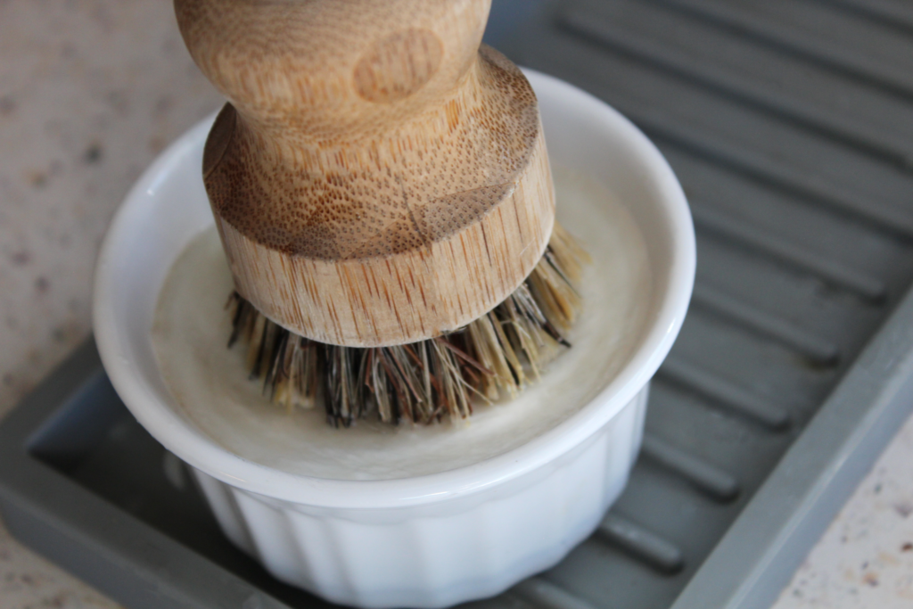 Solid dish soap in a ramekin with a bamboo brush on top