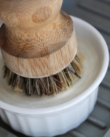 Solid dish soap in a ramekin with a bamboo brush on top