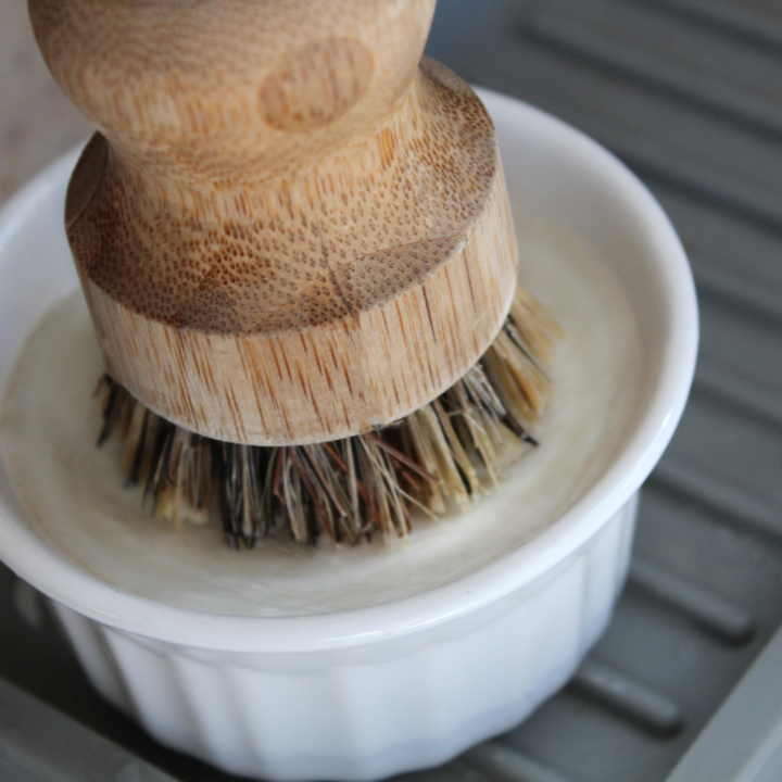 Solid dish soap in a ramekin with a bamboo brush on top