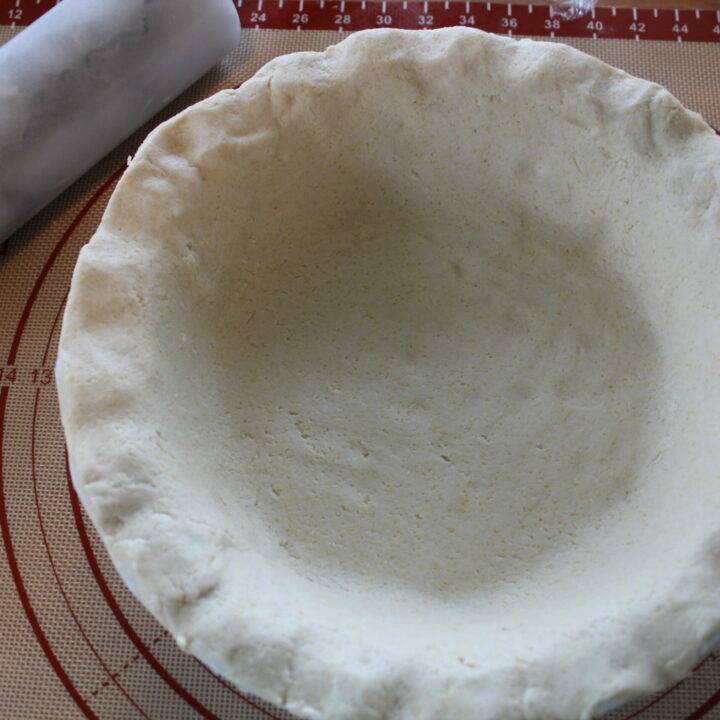 Gluten-free pie crust on a rolling mat in a pie tin