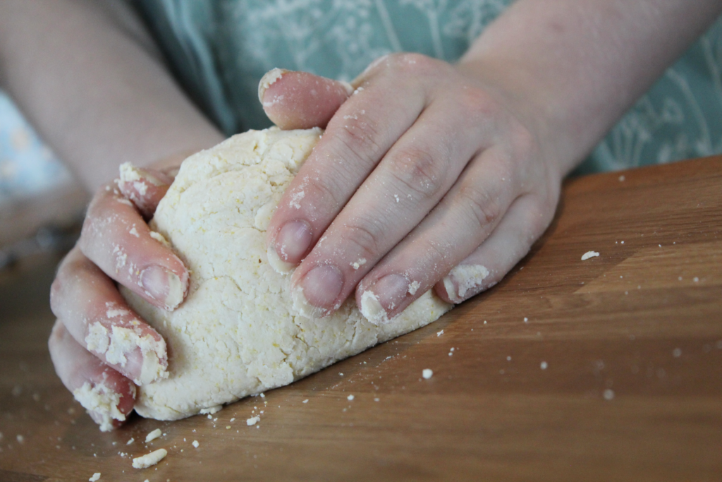 closeup of working pie dough by hand