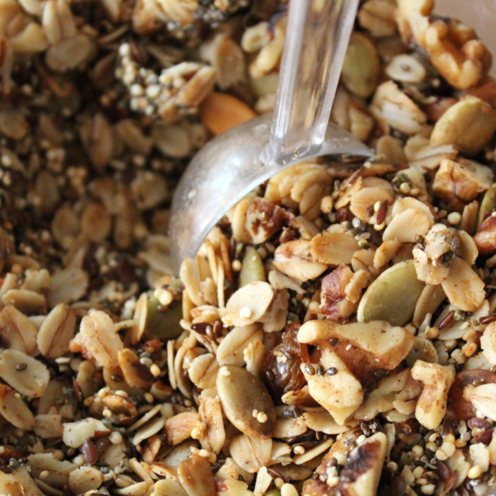 Spoon picking up granola out of a container.